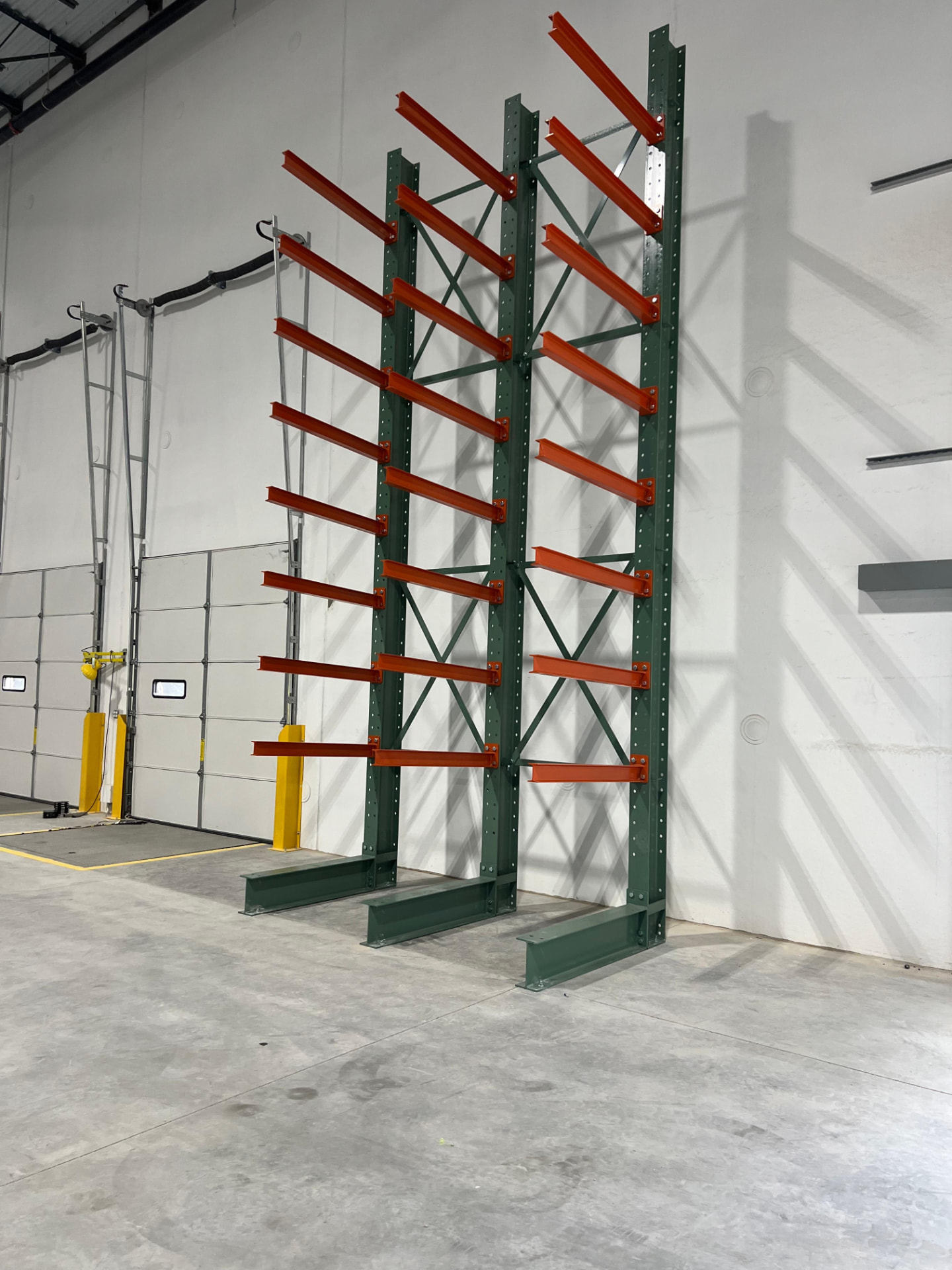 Green cantilever racking frames against a white wall with orange arms