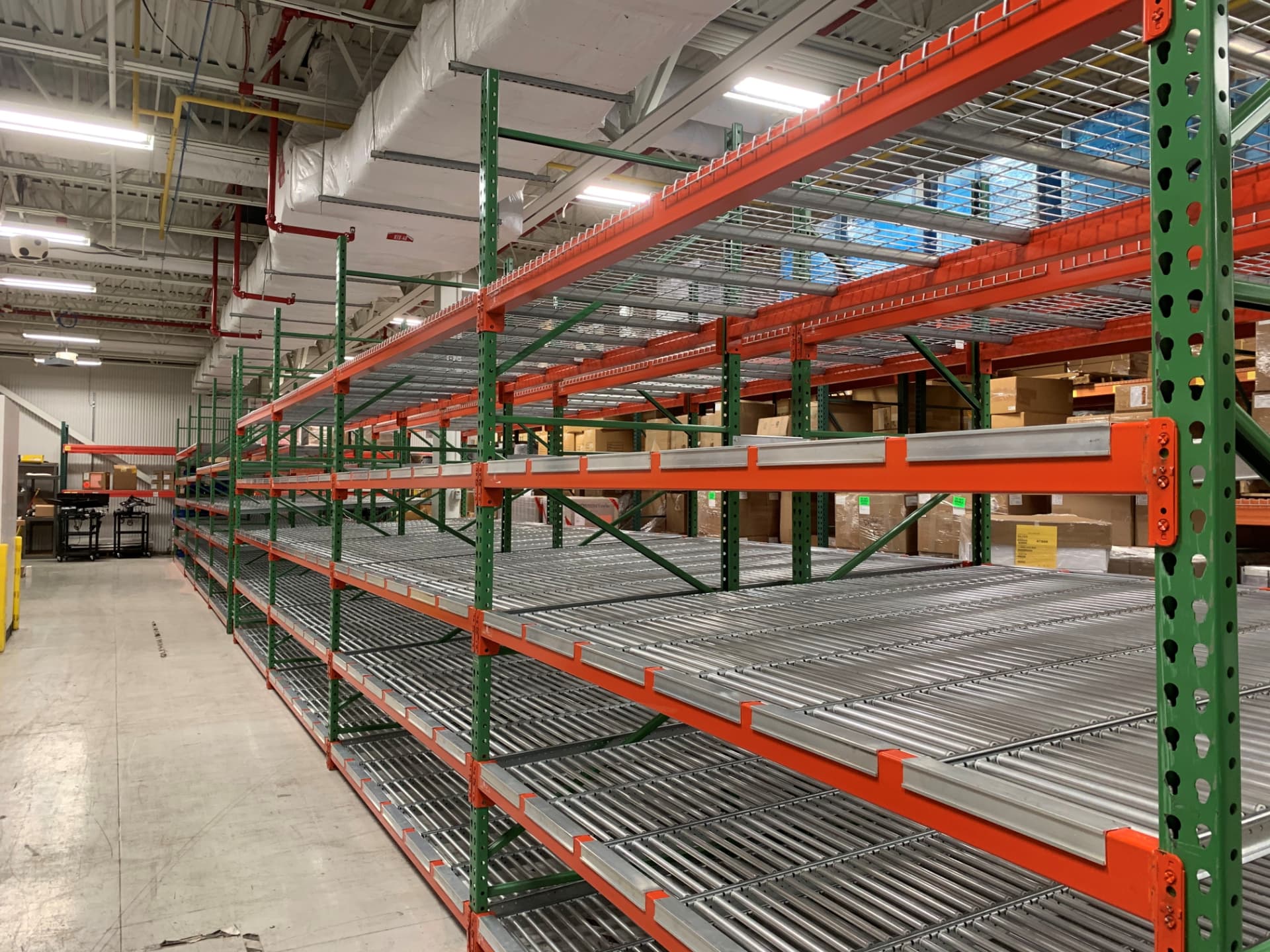 Long row of green and orange carton flow racking with gravity roller lanes