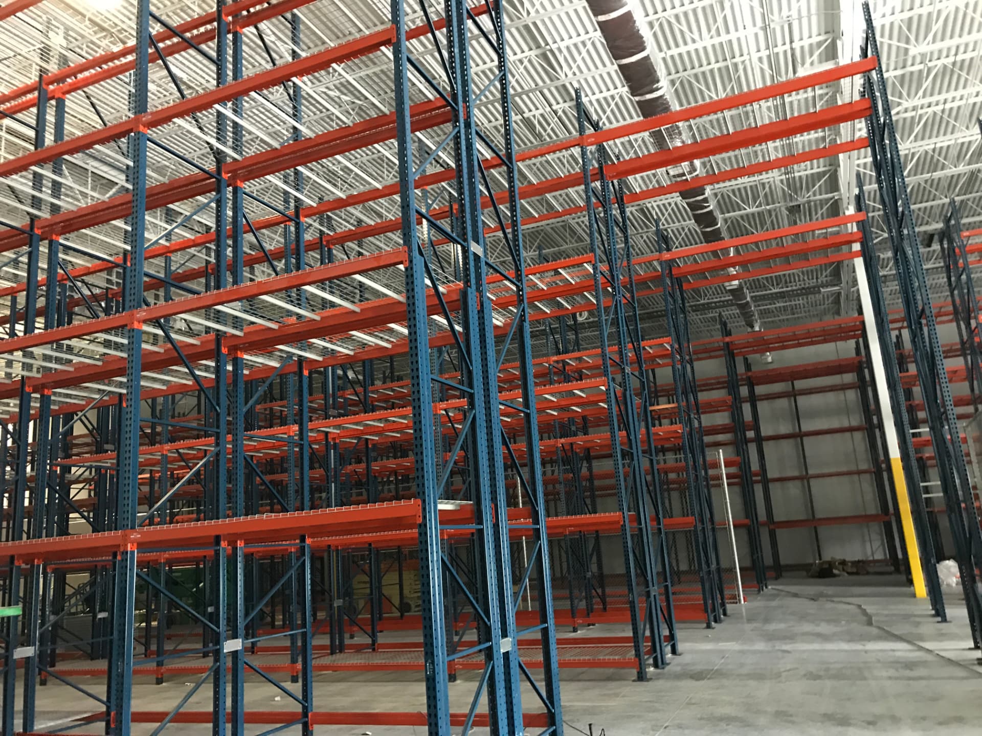 Large-scale installation of blue and orange pallet racking frames