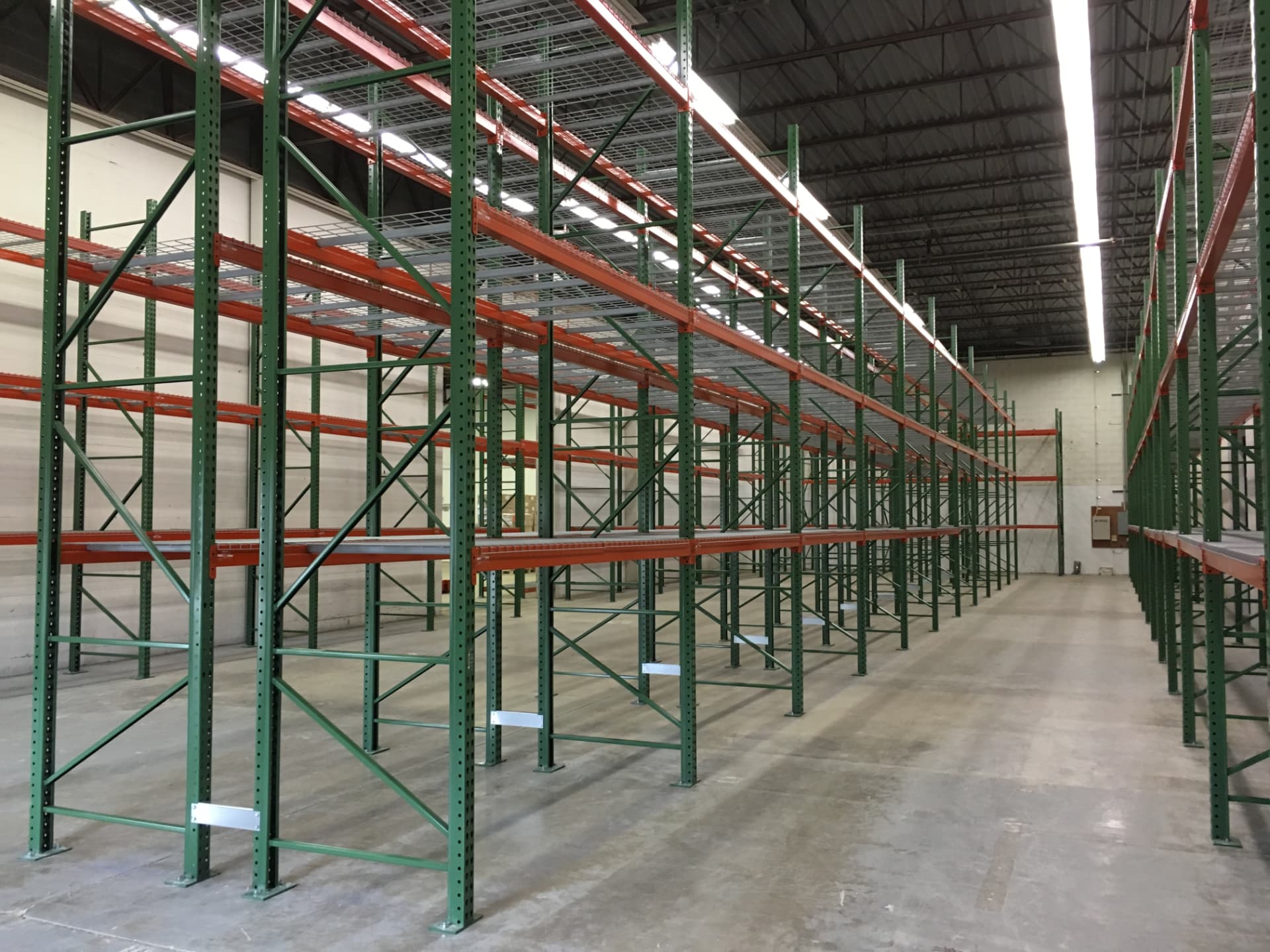 Close up view of empty green pallet rack uprights and orange beams