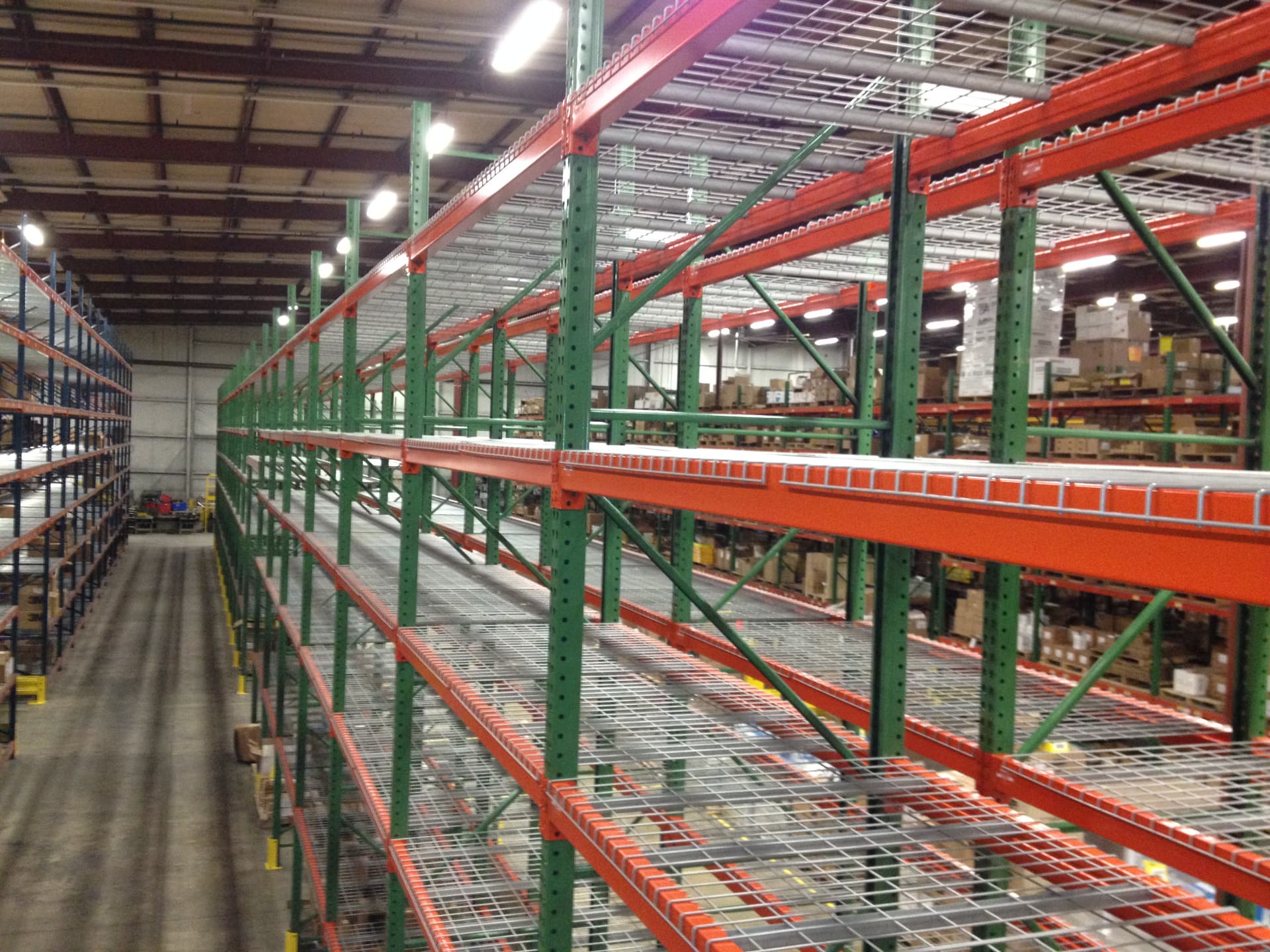 Wide view of orange and green industrial pallet racks in a warehouse