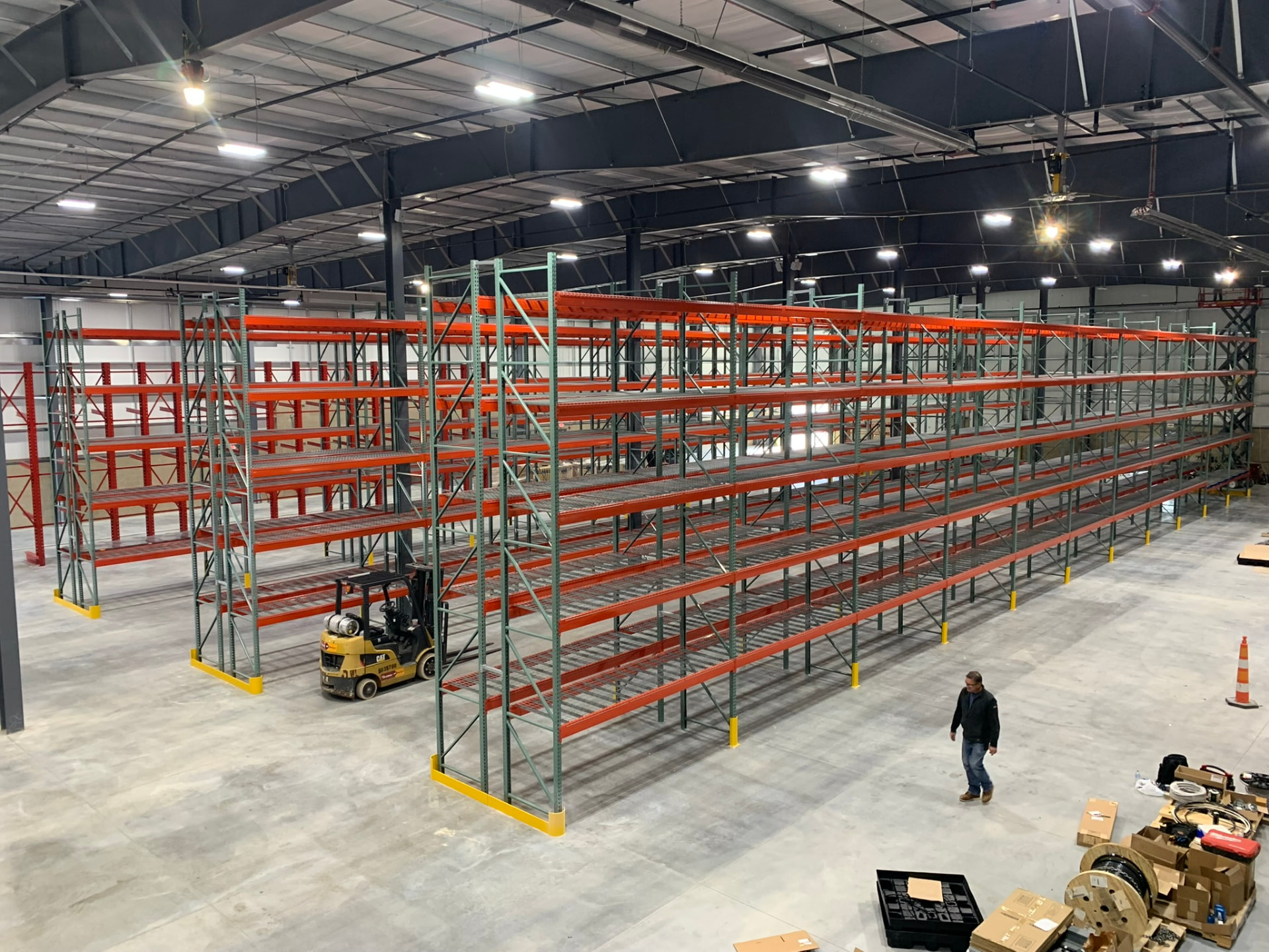 High angle shot of a warehouse floor with several rows of orange and green pallet racks